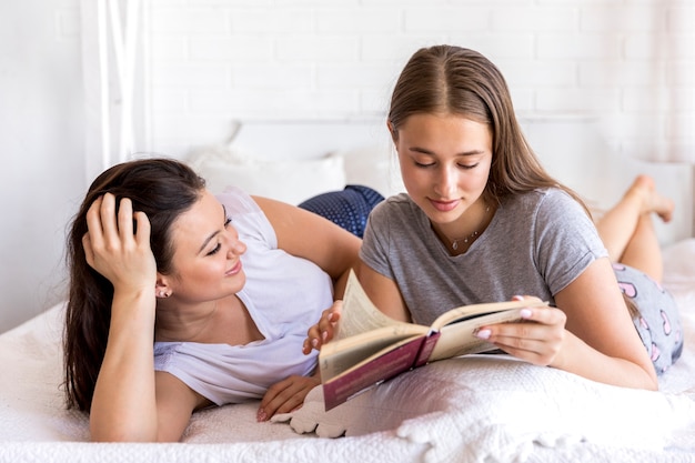 Kostenloses Foto nette frauen, die ein buch auf dem bett lesen