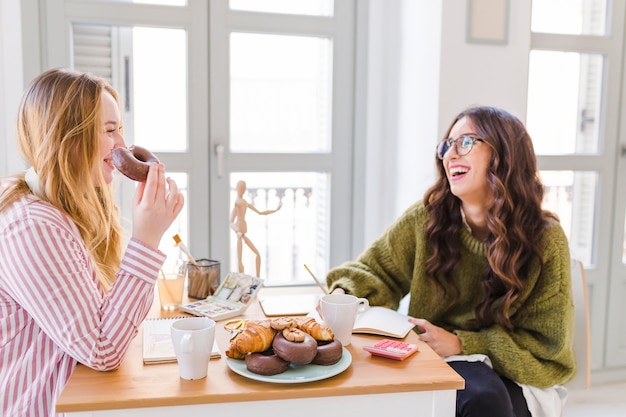 Nette Frauen, die Gebäck zeichnen und essen