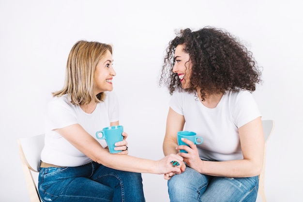 Kostenloses Foto nette frauen, die mit bechern sitzen