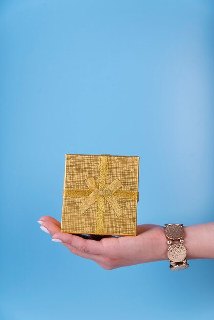 Nette Geschenkbox in der Hand gehalten auf blauem Hintergrund