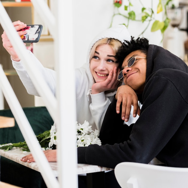 Nette glückliche zwischen verschiedenen Rassen jugendliche junge Paare, die selfie am Handy nehmen