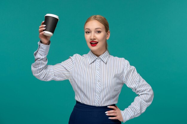 Nette junge blonde Frau der Geschäftsdame im Bürooutfit und in den Gläsern, die Kaffeetasse anheben