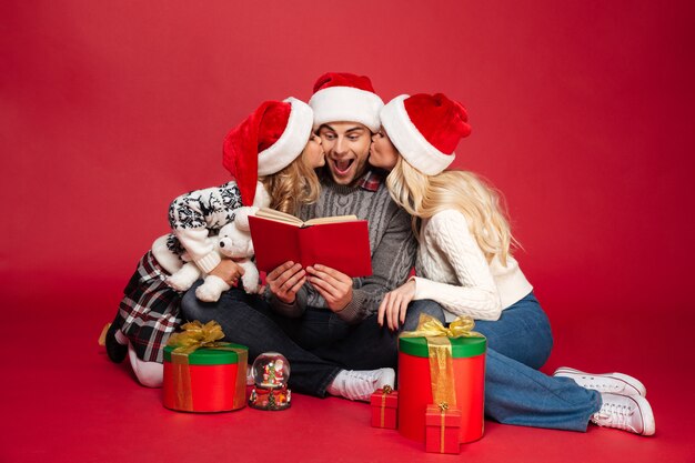 Nette junge Familie, die Weihnachtshüte trägt