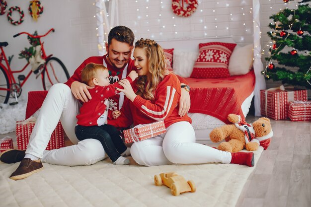 Nette junge Familie, die zu Hause auf einem Bett sitzt