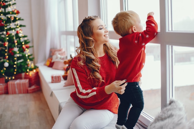 Nette junge Familie, die zu Hause nahe Fenster sitzt