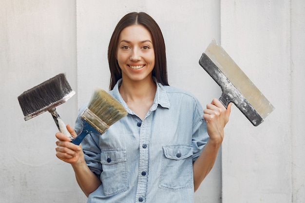 Nette junge Frau, die nahe Wand mit Bürsten steht