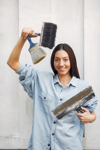 Nette junge Frau, die nahe Wand mit Bürsten steht