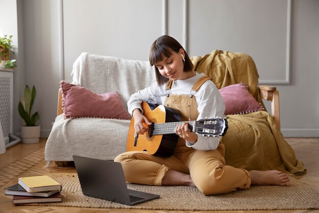 Nette junge Frau, die zuhause Gitarre spielt