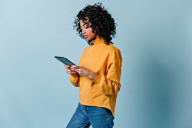 Nette junge Frau in Jeans mit digitaler Tablette