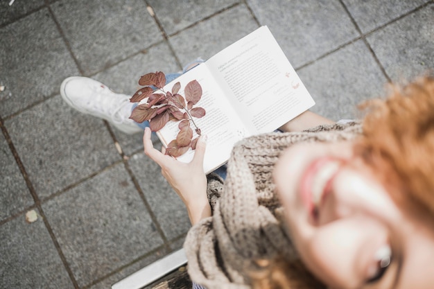 Nette junge frau mit buch- und herbstblättern