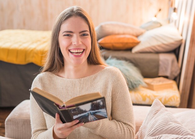 Nette junge lachende Frau während Lesebuch zu Hause