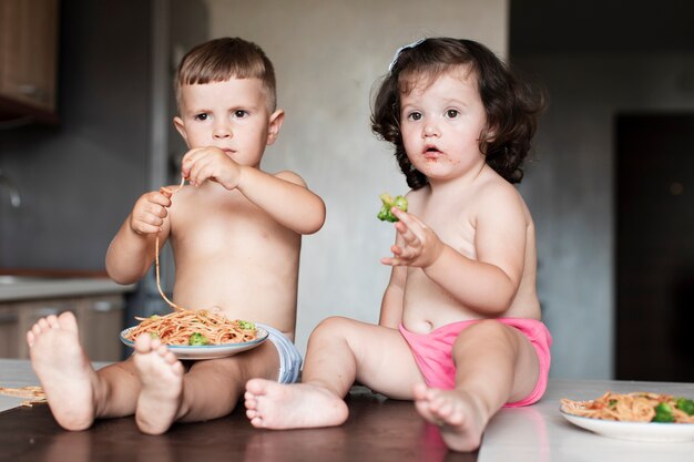 Nette Kinder, die auf dem Tisch sitzen und weg schauen