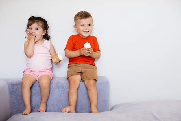 Nette Kinder, die ihre Eiscreme sitzen und genießen