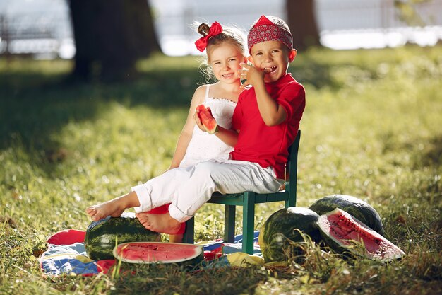 Nette kleine Kinder mit Wassermelonen in einem Park