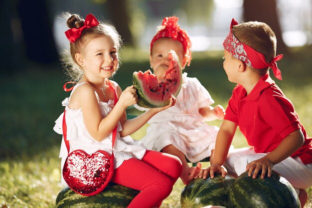 Nette kleine Kinder mit Wassermelonen in einem Park