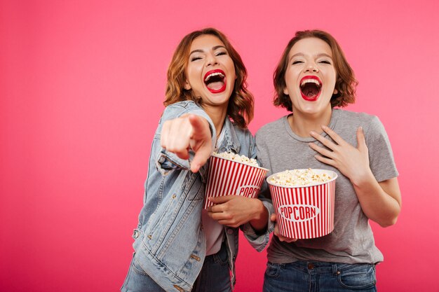 Nette lachende Freundinnen, die das Popcornuhr-Filmzeigen essen.