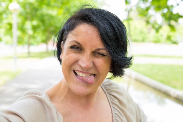 Nette lustige Frau, die selfie Gesicht verzieht und nimmt