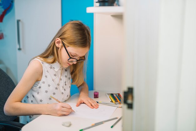 Nette Mädchenzeichnung mit Bleistift am weißen Tisch