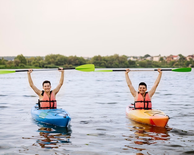 Nette Männer, die Kajakruder obenliegend genießt das Kayak fahren halten