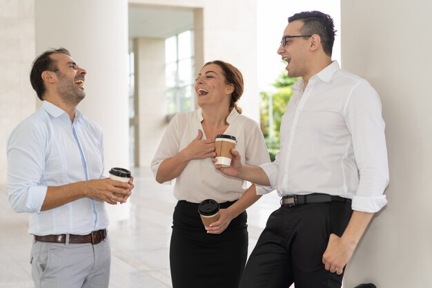 Nette mittlere erwachsene Geschäftskollegen, die über Kaffeepause lachen