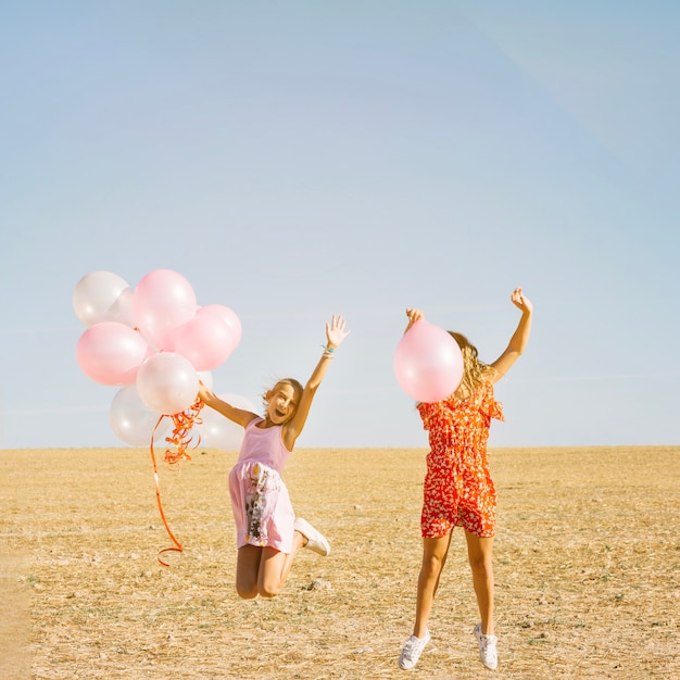 Nette Schwestern, die mit Ballonen springen