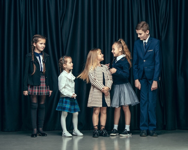 Nette stilvolle Kinder auf Dunkelheit. schöne jugendlich Mädchen und Jungen, die zusammen stehen