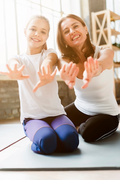 Nette Tochter und Mutter, die auf Yogamatten aufwerfen