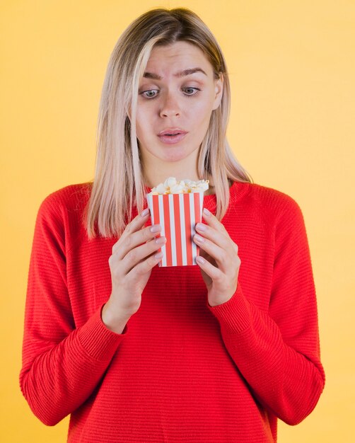 Nette überraschte Frau, die Popcorntasche hält