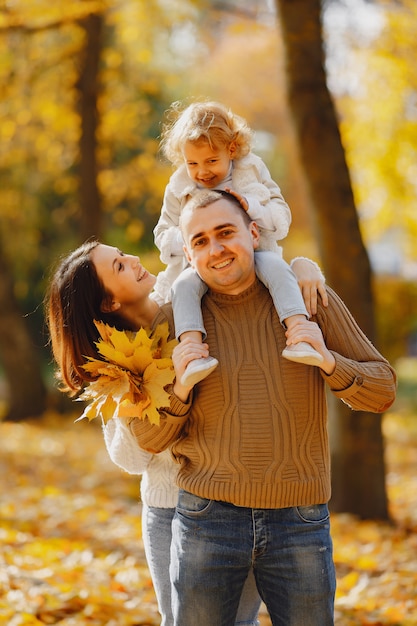 Nette und stilvolle Familie, die in einem Herbstfeld spielt