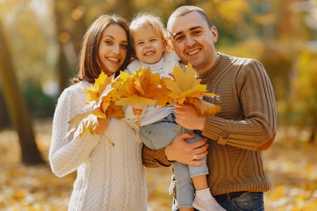 Nette und stilvolle Familie, die in einem Herbstfeld spielt