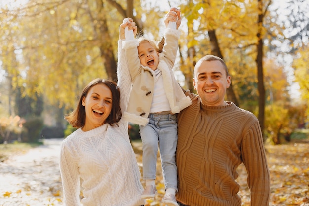 Nette und stilvolle Familie, die in einem Herbstfeld spielt