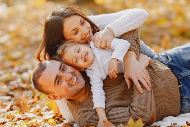 Nette und stilvolle Familie, die in einem Herbstfeld spielt