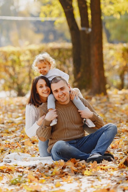 Nette und stilvolle Familie, die in einem Herbstfeld spielt