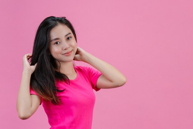 Nette weiße asiatische Frau wirft sich mit einem rosa Haar auf einem Rosa auf.