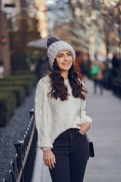 Netter Brunette in einer weißen Strickjacke in einer Stadt