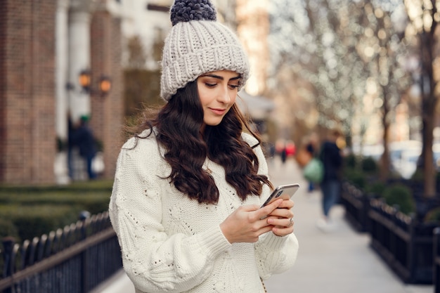 Netter Brunette in einer weißen Strickjacke in einer Stadt