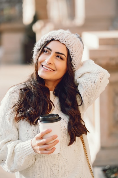 Netter Brunette in einer weißen Strickjacke in einer Stadt