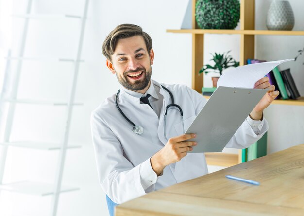 Netter Doktor mit Klemmbrett im Büro