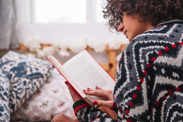 Netter Jugendlicher, der das Lesen auf Bett genießt