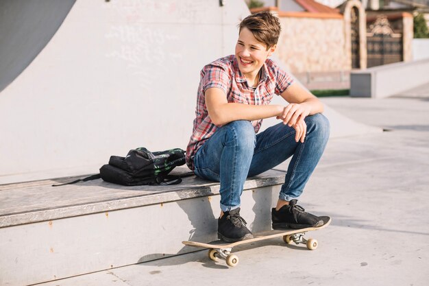 Netter Jugendlicher, der Füße auf Skateboard hält