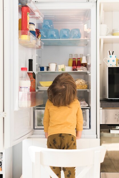 Netter Junge, der hohen Kühlschrank untersucht