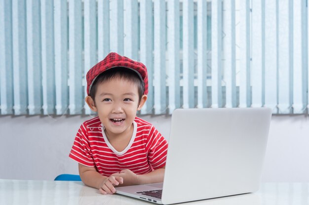 Netter Junge, der labtop im Kinderzimmer spielt