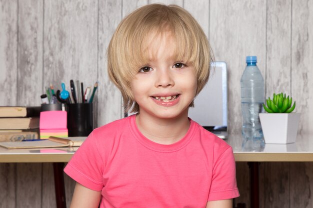 Netter Junge im rosa T-Shirt, das zu Hause lächelt