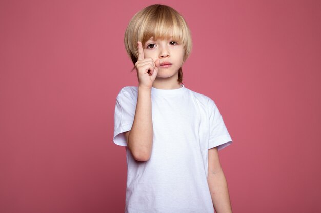 Netter Junge im weißen T-Shirt entzückendes kleines Kind auf rosa Wand