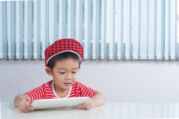 Netter Junge spielt Tablette im Kinderzimmer