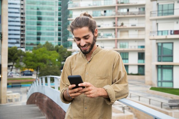 Netter junger Mann, der Smartphone verwendet