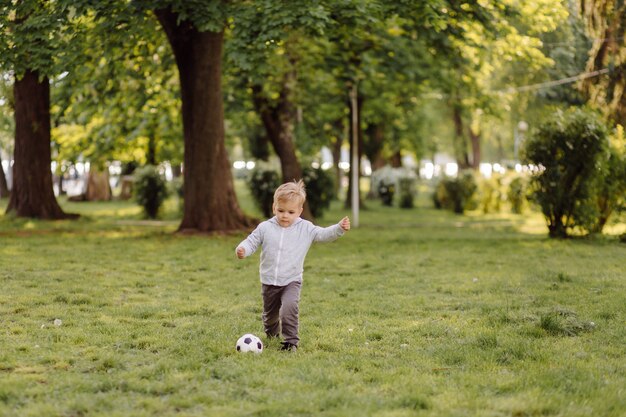 Netter kleiner Junge, der draußen Fußball spielt