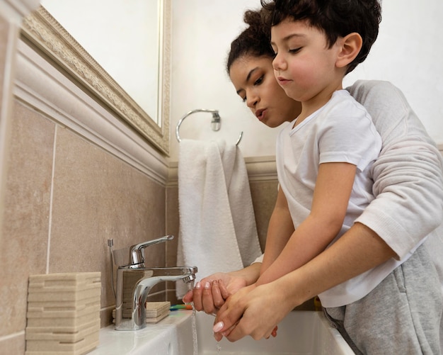 Netter kleiner Junge, der Hände mit seiner Mutter wäscht