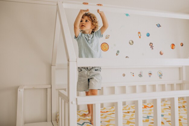 Netter kleiner Junge, der Spaß im Bett in Form eines Hauses hat