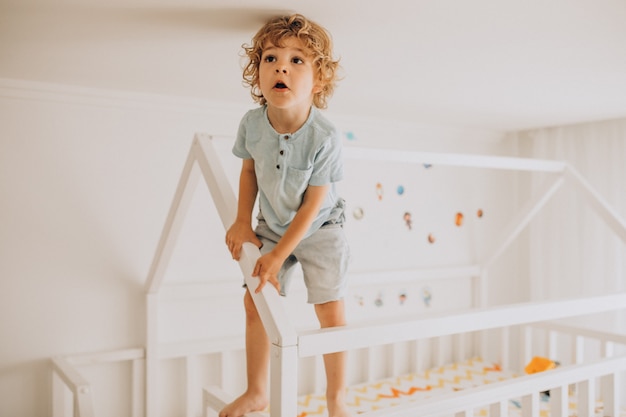 Netter kleiner Junge, der Spaß im Bett in Form eines Hauses hat